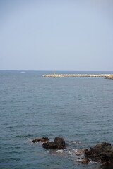 A yellow lighthouse on the blue sea.
It is with black basalt.