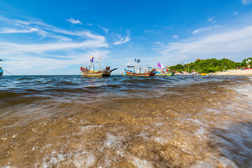 Fishing boat on the sea wave beach with blue sky background