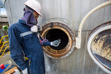 Worker hand holding gas detector inspection safety gas testing at front manhole stainless tank