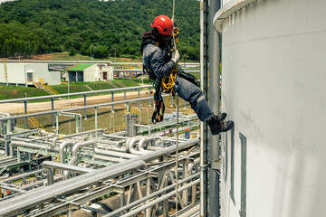 Male worker rope access height safety inspection of thickness storage tank