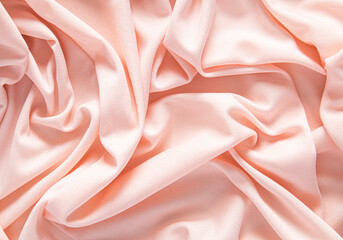 Elegant satin fabric with a peachy color. luxurious texture of the soft folds . festive background....