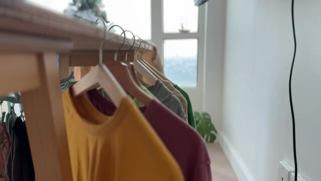 Close up video footage 4k of woman hanging colorful t-shirt in the apartment.