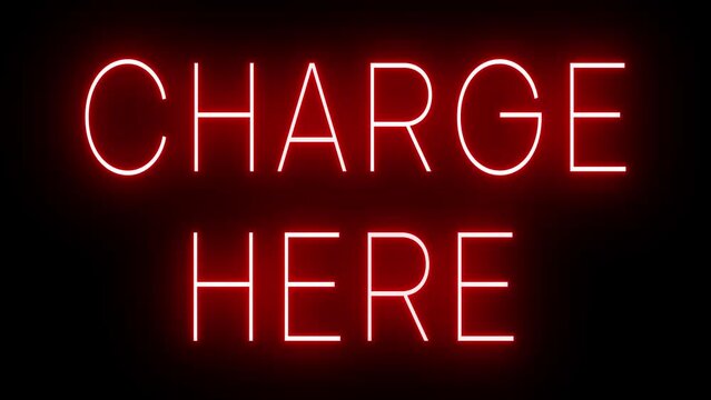 Flickering red retro style neon sign glowing against a black background for CHARGE HERE