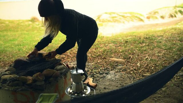 Campfire, nature and cooking, woman with breakfast on adventure to relax with camper van at ocean. Camping, morning toast at fire and girl on travel holiday at beach with freedom, peace and food.