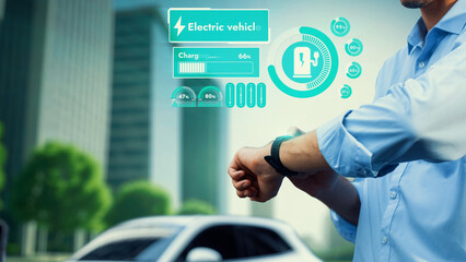 Businessman check EV car battery status on smartwatch hologram recharge from charging station ESG...