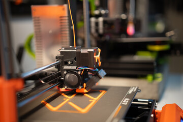 Home studio. 3D printers at work. Production, passion and hobby. Orange plactic filament.
