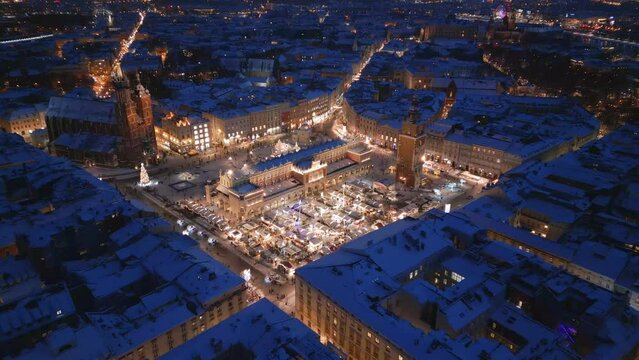 Krakow winter Main Market Square covered with snow aerial drone view of monuments - Saint Mary Church, Sukiennice (Cloth Hall), City Hall Tower, Wawel