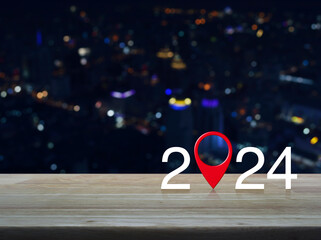 2024 letter with map pin location icon on wooden table over blur colorful night light city tower...
