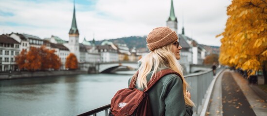 Blonde tourist girl exploring Zurich, Switzerland in autumn with a backpack and warm clothing.