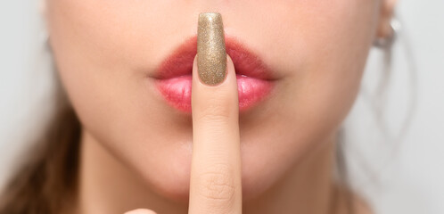 Female hands with long nails with glitter nail polish. Long gold nails near face. Stylish fashion...