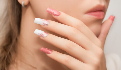 Female hands with long nails with glitter nail polish. Long nails peach color near face. Stylish...