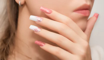  Female hands with long nails with glitter nail polish. Long nails peach color near face. Stylish fashion manicure. © devmarya