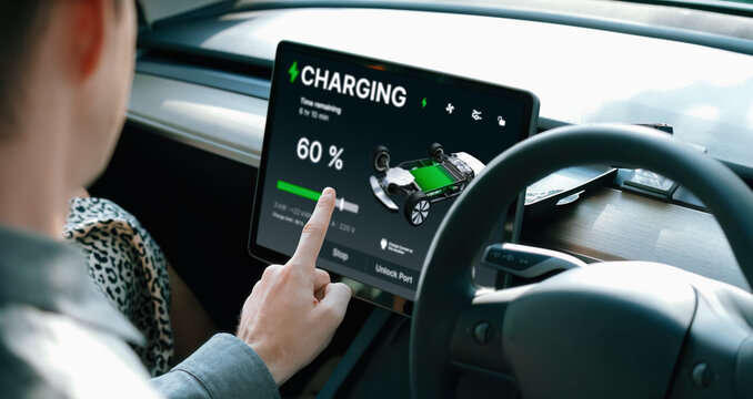 Electric car driver checks battery charging status, range and charging limit on app screen in the car. Smart technology device show EV car recharging data of electric storage in car battery innards.