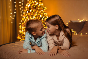 Twins boy and girl, brother and sister, at home waiting for the New Year holiday in the bedroom on...