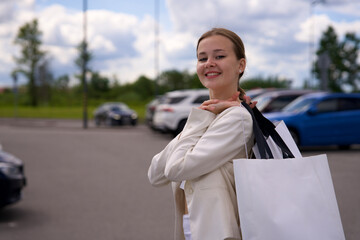 Young happy beautiful woman, elegant girl is shopping in the outdoors mall holding bags in hand on...