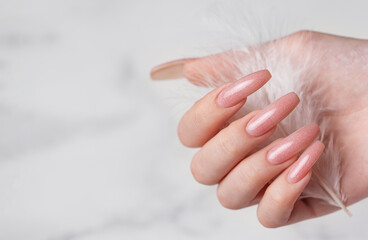 Female hands with pink nail design  hold a feather