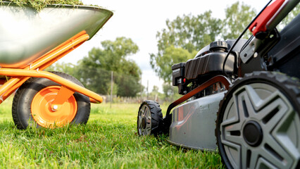 lawn mower with lawn wheelbarrow on a green lawn