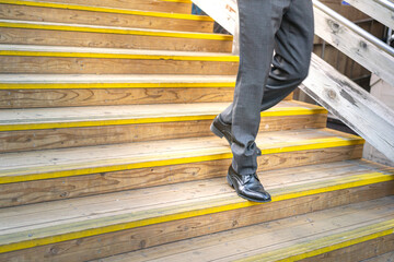 A businessman in formal uniform suit and leather court shoe is walking down on the stair with hurry...