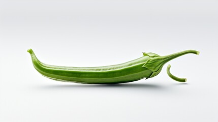 A single fresh okra, its green surface and unique shape contrasted sharply against a clean white scene.