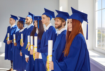 Group of happy smiling diverse multiethnic college or university students in traditional blue caps...