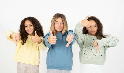 Three beautiful multiracial kid girls  showing thumbs up and thumbs down, difficult choose concept