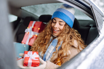 Young woman rides in the back seat of a car and holds a New Year's gift in her hands. Great winter...