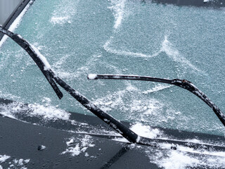 Windshield of car is covered with light snow and wipers are raised from glass - obrazy, fototapety, plakaty