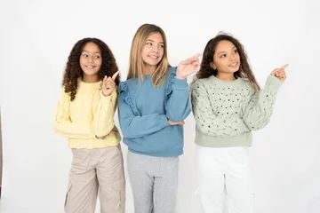 Fotobehang Photo of attractive Three beautiful multiracial kid girls  direct finger empty space cheap dentistry © Roquillo