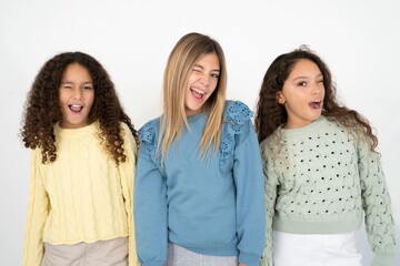 Three beautiful multiracial kid girls  winking looking at the camera with sexy expression, cheerful and happy face. - obrazy, fototapety, plakaty