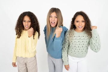 Three beautiful multiracial kid girls  angry and mad raising fist frustrated and furious while...