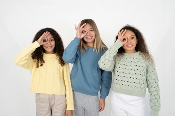 beautiful multiracial kid girls  doing ok gesture with hand smiling, eye looking through fingers with happy face.