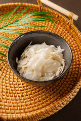 Dried coconut chips in a bowl on a dark background vertical photo