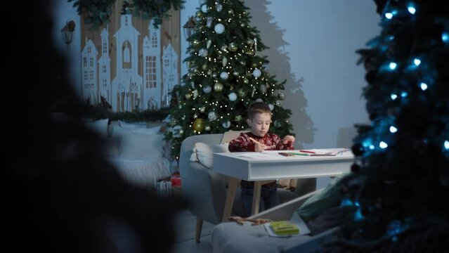 Festive Joy: Child Drafts Santa Letter, Happy Anticipation in a Decorated Home, Eager for Presents. High quality 4k footage