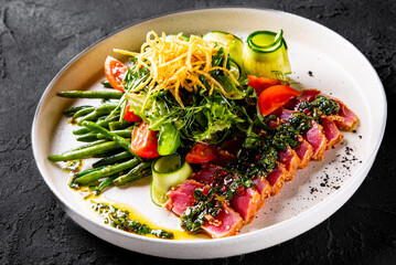 tuna slices with fresh vegetables and green beans salad on a plate.