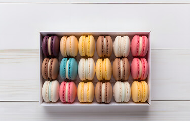 colorful macarons in white box on white wooden table top view