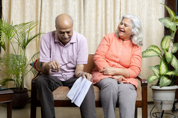 Obraz premium Happy indian senior,couple looking in to the policy papers and smiling, After Retirement policy cover