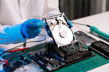 Obraz premium Hard disk drive on the technician's desk and a computer motherboard as a component. the concept of data, hardware, and information technology...