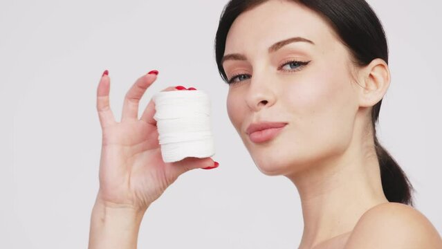 Charismatic, beautiful young woman using cosmetology cotton pads, isolated on the background. Advertising concept for clean skin, facial care and natural cosmetics.