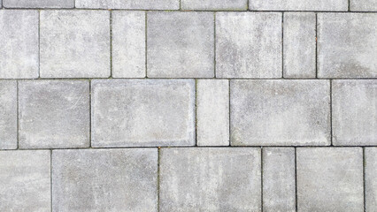  Close up of pebbly gray cement bricks paving a textured road.
