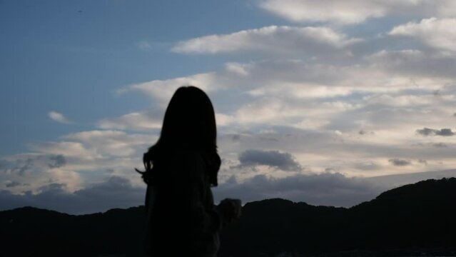 Silhouette of a woman drinking coffee while watching beautiful view in the morning
