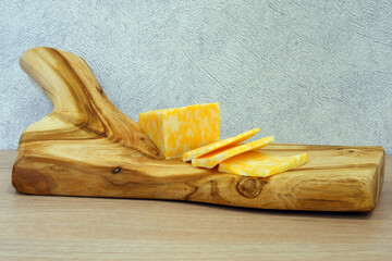 Cutting board. Made by hand from cherry wood. Bright and beautiful texture. There is cheese and salted lard on the board. It looks tasty and appetizing. Great for background.
