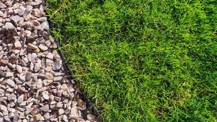  Lush green lawn with a border of garden pebbles - 690961795