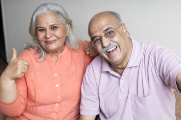 indian senior couple taking selfie with phone at living room, Retired life concept