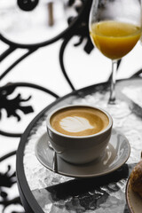 New Year's breakfast on the hotel balcony in the mountains. Coffee with croissant, juice and tangerines against the backdrop of snow-capped mountains. Concept of winter holidays