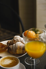 New Year's breakfast on the hotel balcony in the mountains. Coffee with croissant, juice and tangerines against the backdrop of snow-capped mountains. Concept of winter holidays