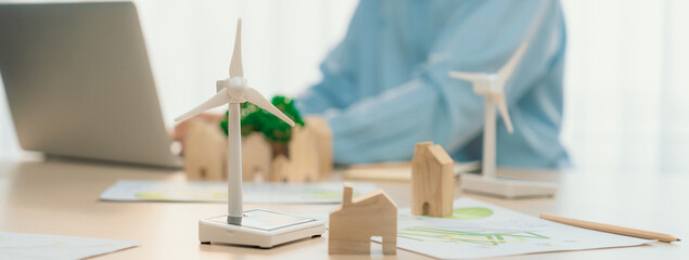 Windmill model represented using clean energy and wooden block represented eco house was scatter...