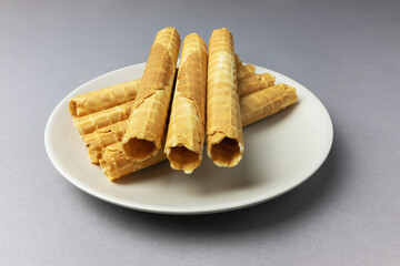 Delicious Buttery Waffle Tubes on Plate Against Gray Background
