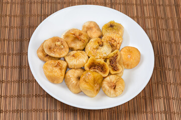 Dried figs on white dish on the bamboo place mat