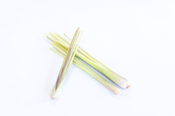 A close up of three fresh lemongrass stalks crossed over each other on a white background
