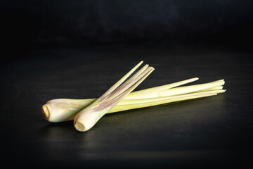 Two stalks of fresh lemongrass on a black background